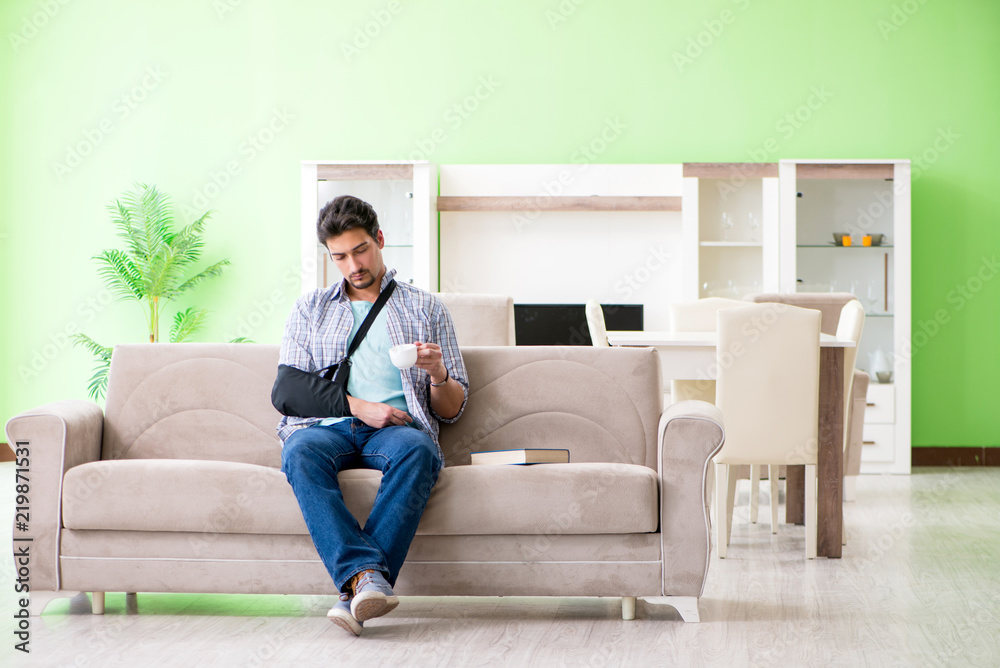 Young student man with hand injury sitting on the sofa 