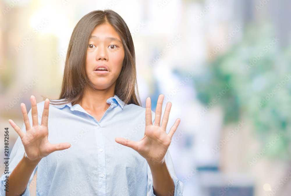 Young asian business woman over isolated background afraid and terrified with fear expression stop gesture with hands, shouting in shock. Panic concept.