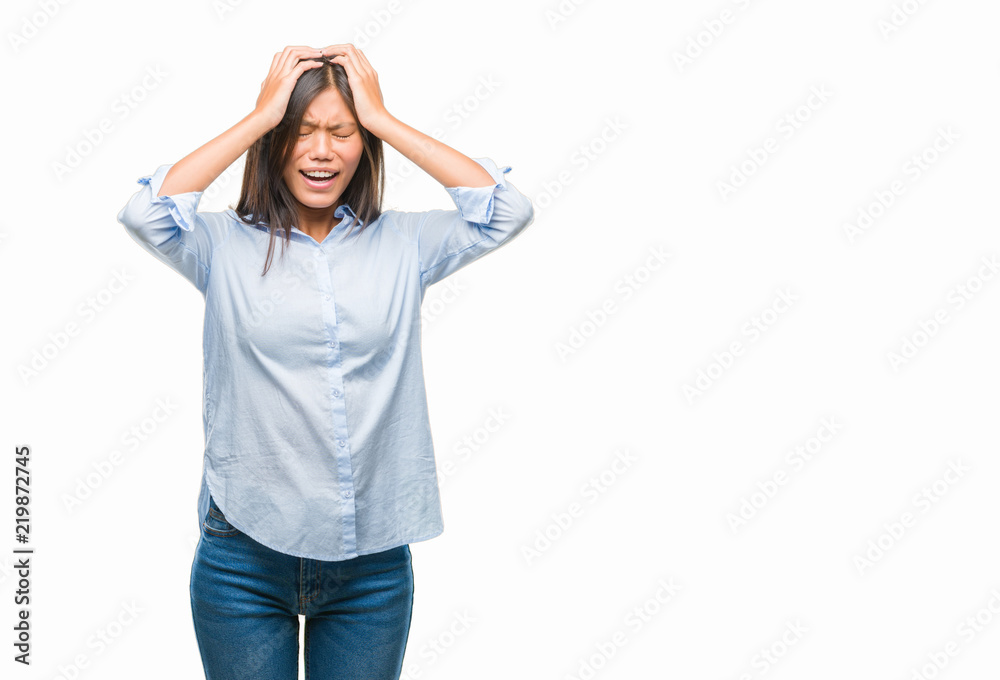 Young asian business woman over isolated background suffering from headache desperate and stressed because pain and migraine. Hands on head. Young asian business woman over isolated background suffering from headache desperate and stressed because pain and migraine. Hands on head.