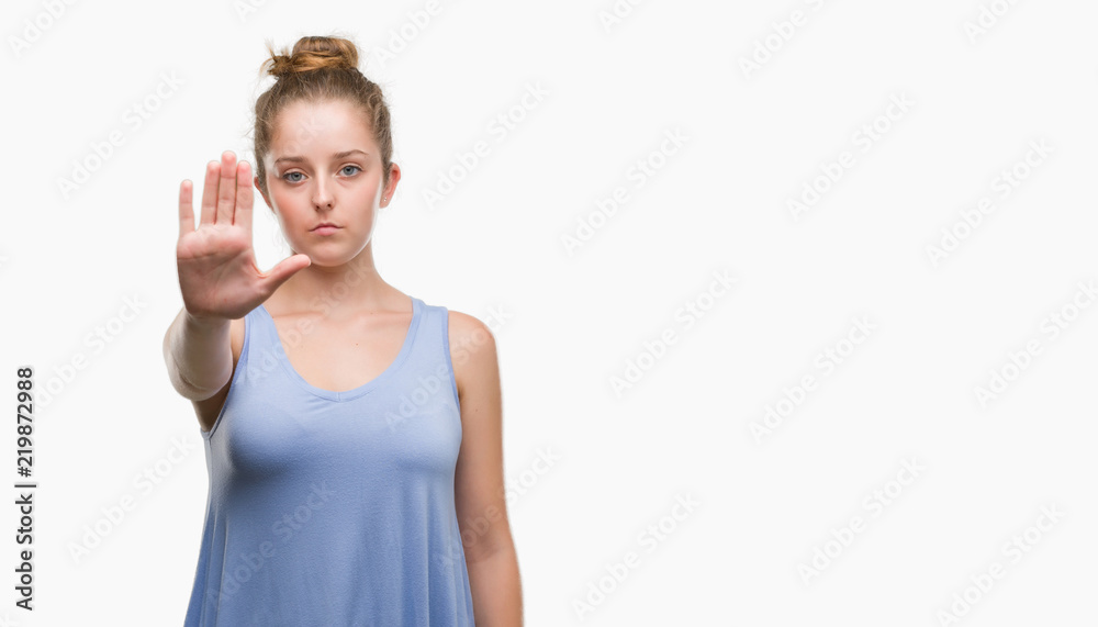 Young blonde woman doing stop sing with palm of the hand. Warning expression with negative and serious gesture on the face.