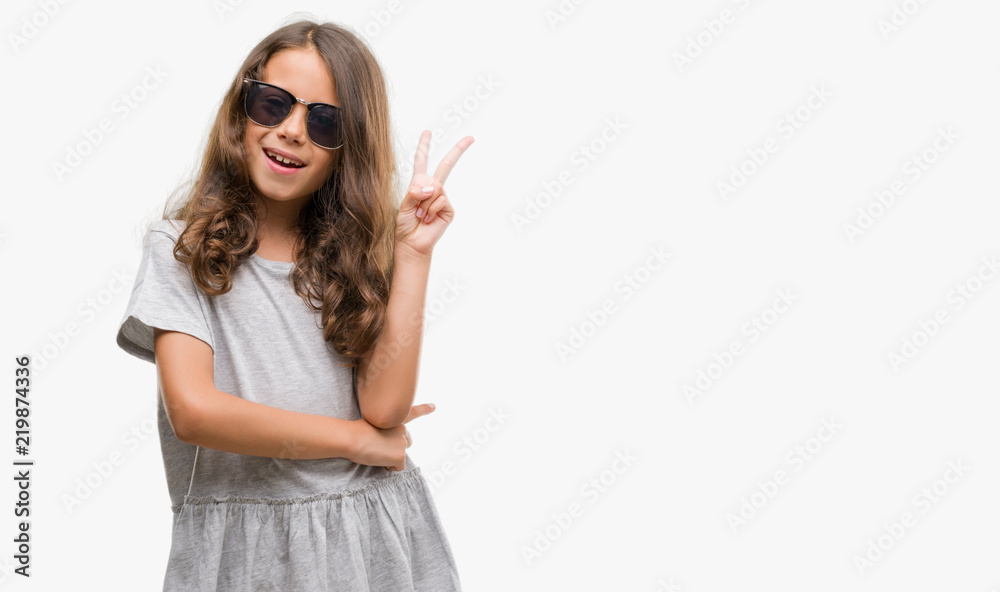 Brunette hispanic girl wearing sunglasses smiling with happy face winking at the camera doing victory sign. Number two. Brunette hispanic girl wearing sunglasses smiling with happy face winking at the camera doing victory sign. Number two.