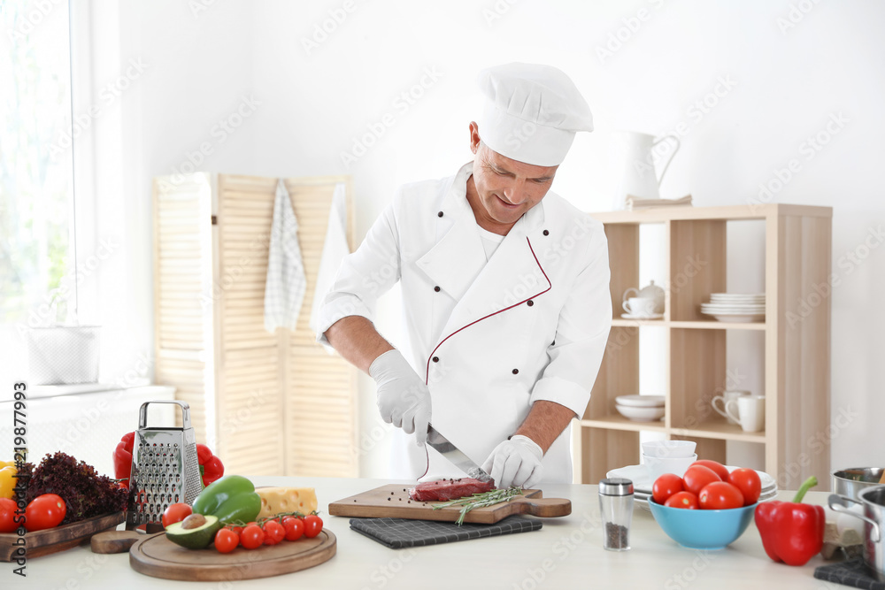 Professional chef cutting meat on table in kitchen Professional chef cutting meat on table in kitchen