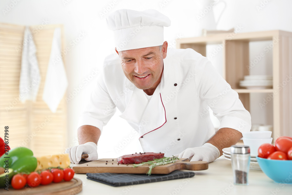 Professional chef cooking meat on table in kitchen Professional chef cooking meat on table in kitchen