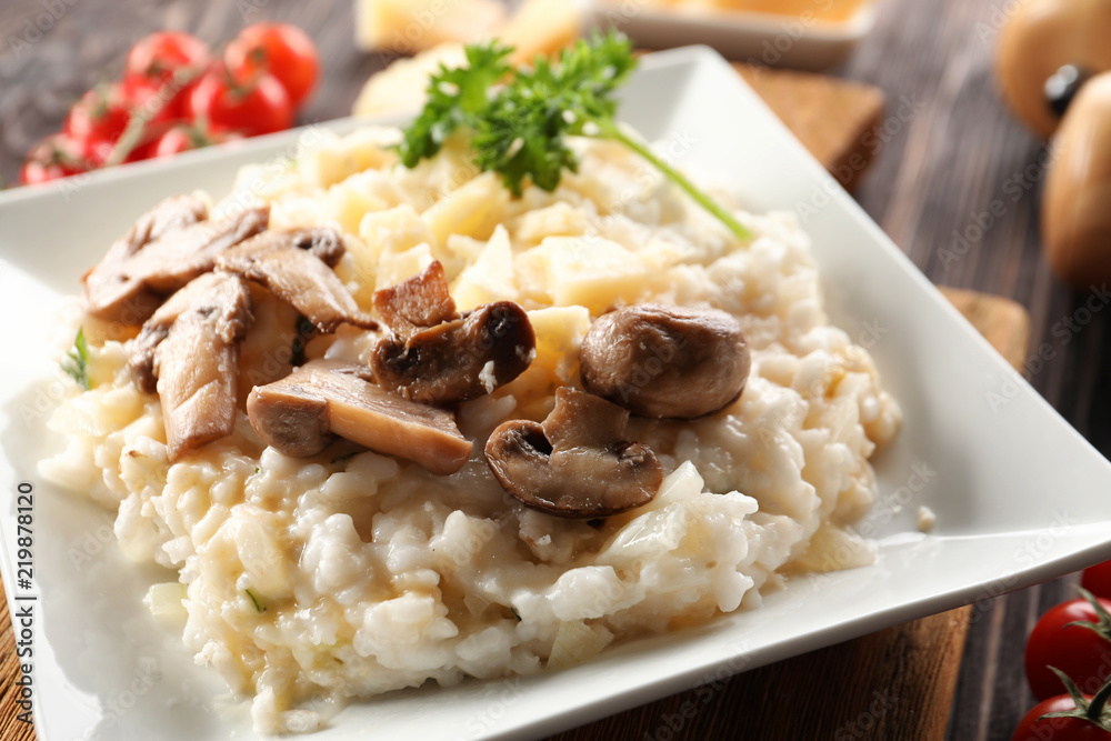 Plate with risotto and mushrooms on table, closeup