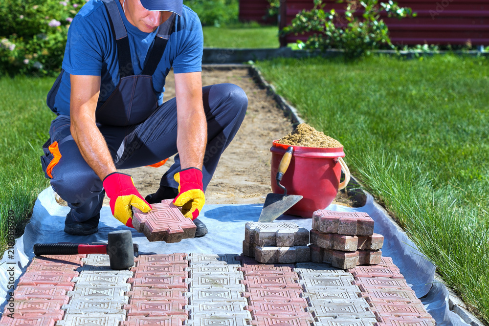 Laying of pavement tiles. Man lays paving slabs in the garden. Stock
