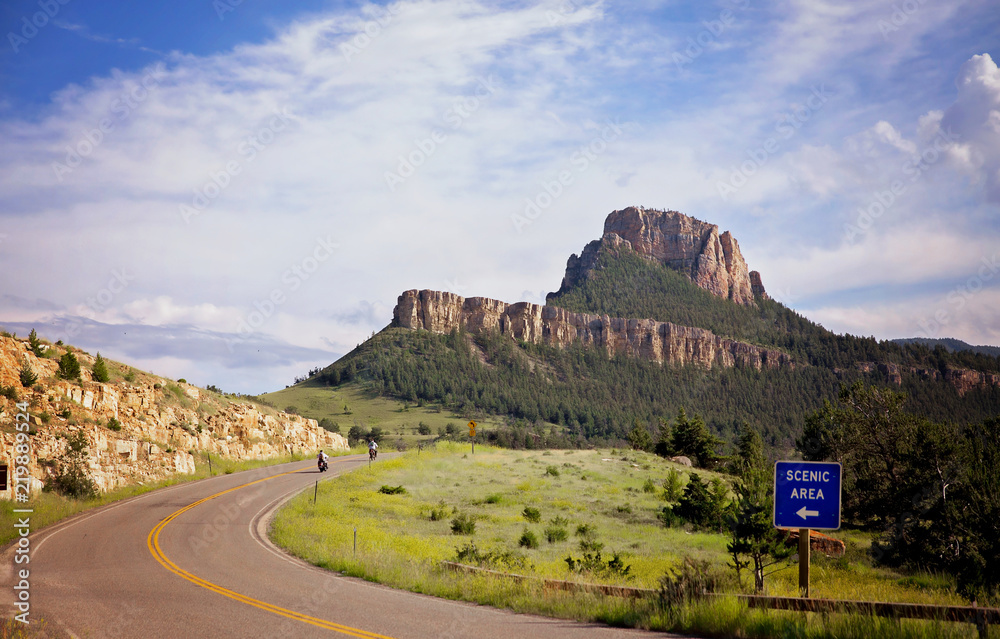 Two motorbikes travelling along a winding highway between mountains in a summer landscape in a Wyoming landscape