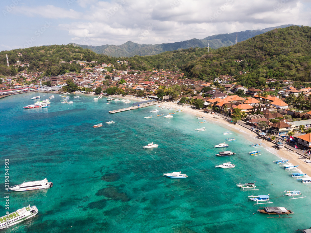 Stunning aerial view of Padang Bai beach, harbor and town in Northeast Bali in the famous Indonesia island on a sunny day.