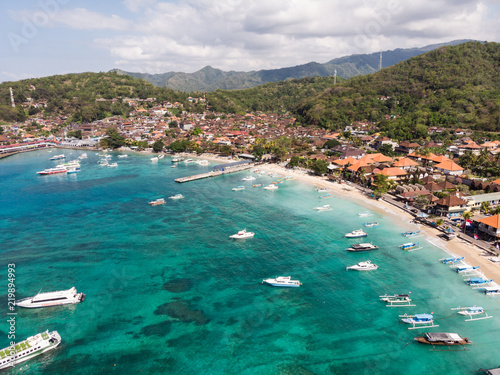 Stunning aerial view of Padang Bai beach, harbor and town in Northeast Bali in the famous Indonesia island on a sunny day.