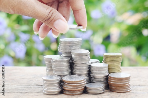 woman hand holding coin with coins stack,selective focus , money saving and investment concept