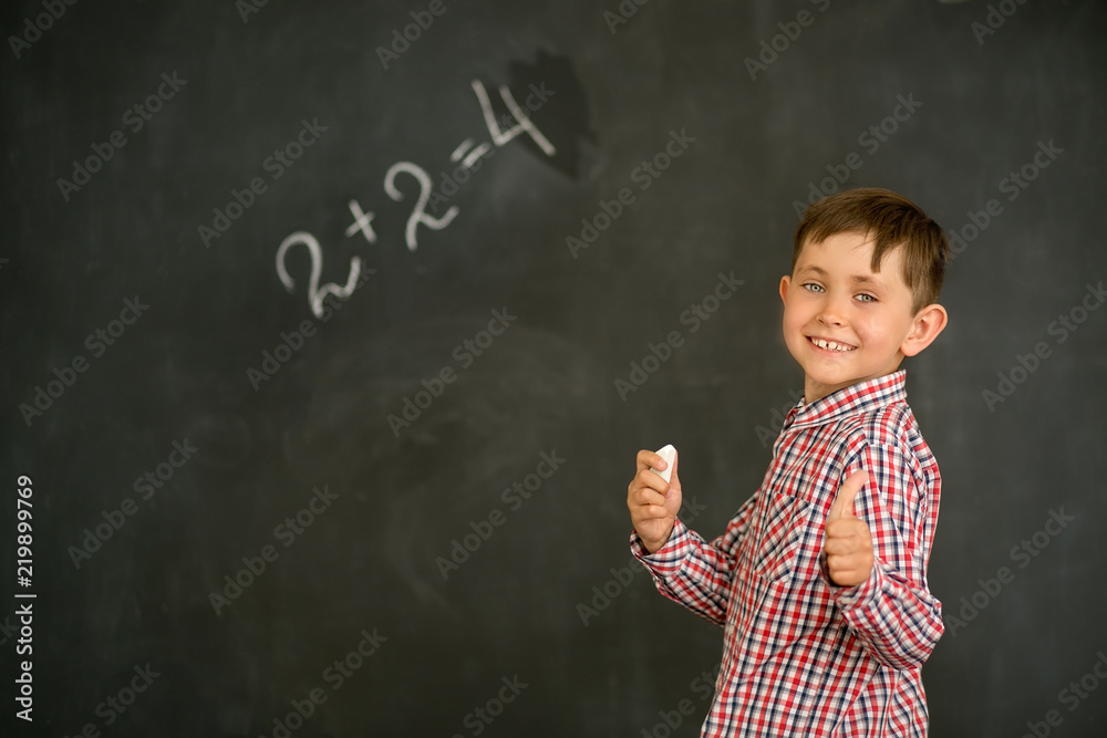 A small and joyful student solved the problem on the board and shows his thumbs up A small and joyful student solved the problem on the board and shows his thumbs up