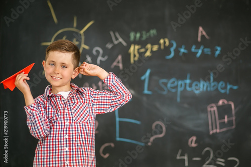 A schoolboy holding a red airplane in the hands of a training board photo