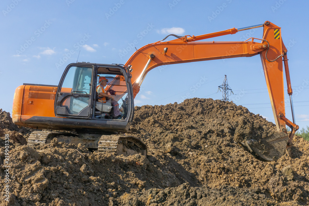 Orange excavator loads the land on a construction site.. Orange excavator loads the land on a construction site..