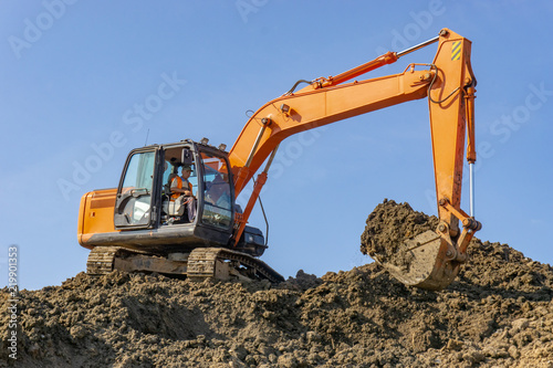 Orange excavator loads the land on a construction site..