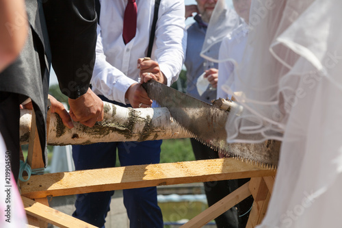 Hochzeitspaar sägt Baumstamm