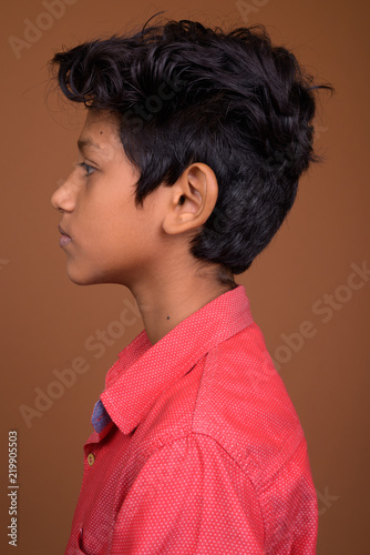 Young Indian boy wearing smart casual clothing against brown bac