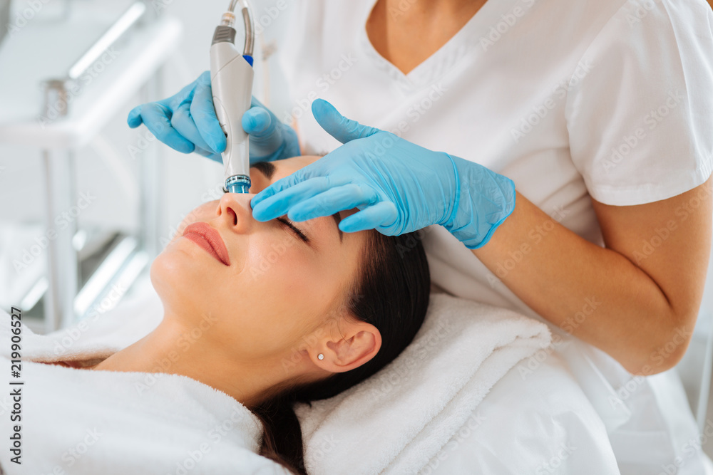 Anti age treatment. Attractive nice woman lying on the medical bed while having beauty procedures Anti age treatment. Attractive nice woman lying on the medical bed while having beauty procedures