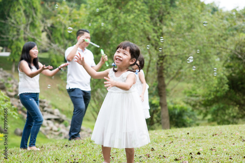 Asian family blowing soap bubbles outdoors