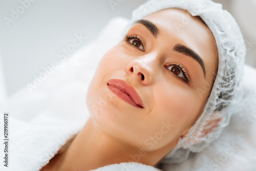 I am ready. Joyful nice woman lying on a medical bed while waiting for a beauty procedure