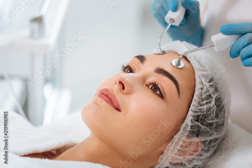 Microcurrent therapy. Pleasant nice woman having a microcurrent therapy while visiting a beauty salon