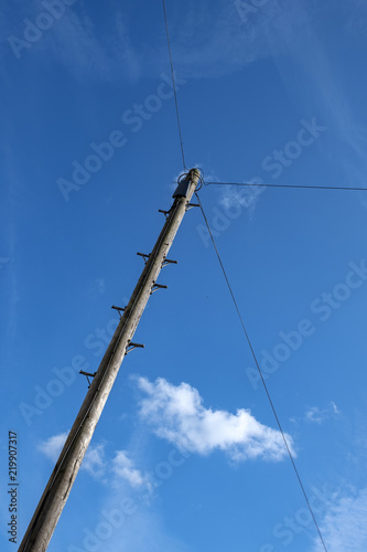 Telephone wiring pole isolated against deep blue sky UK