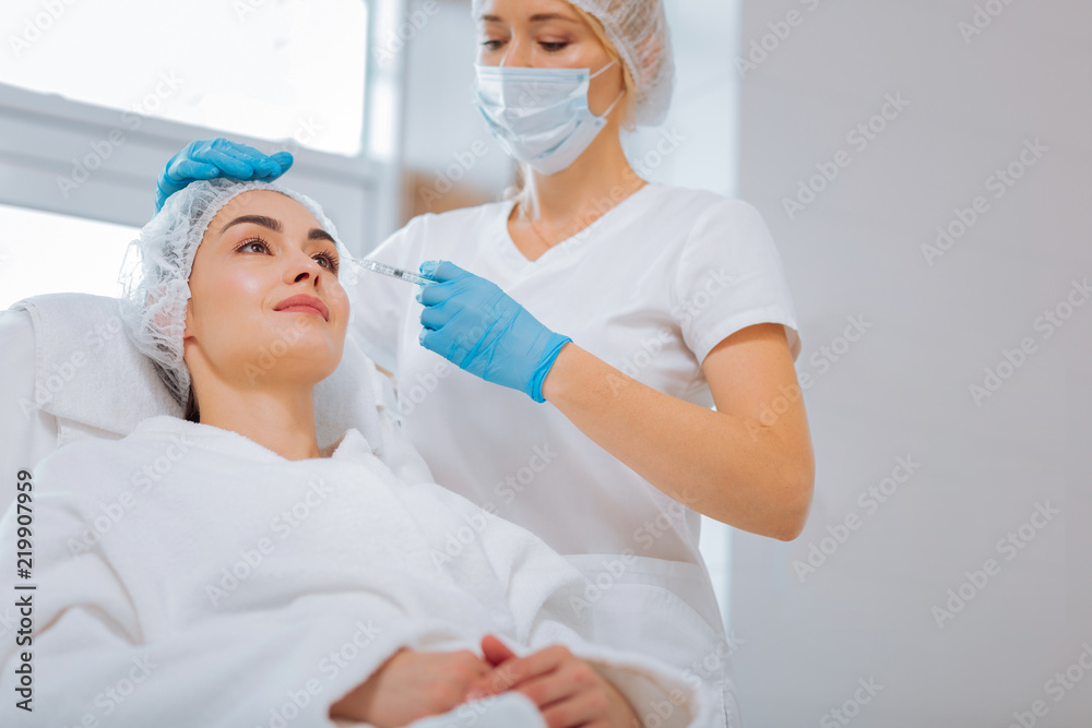 Important procedure. Serious nice beautician focusing on her work while doing an injection Important procedure. Serious nice beautician focusing on her work while doing an injection