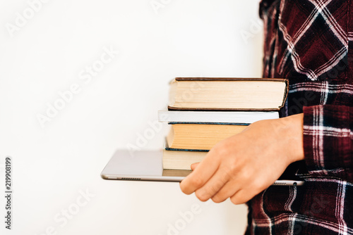 Hands of a girl holding a tablet and a stack of books. The concept of knowledge. copy space