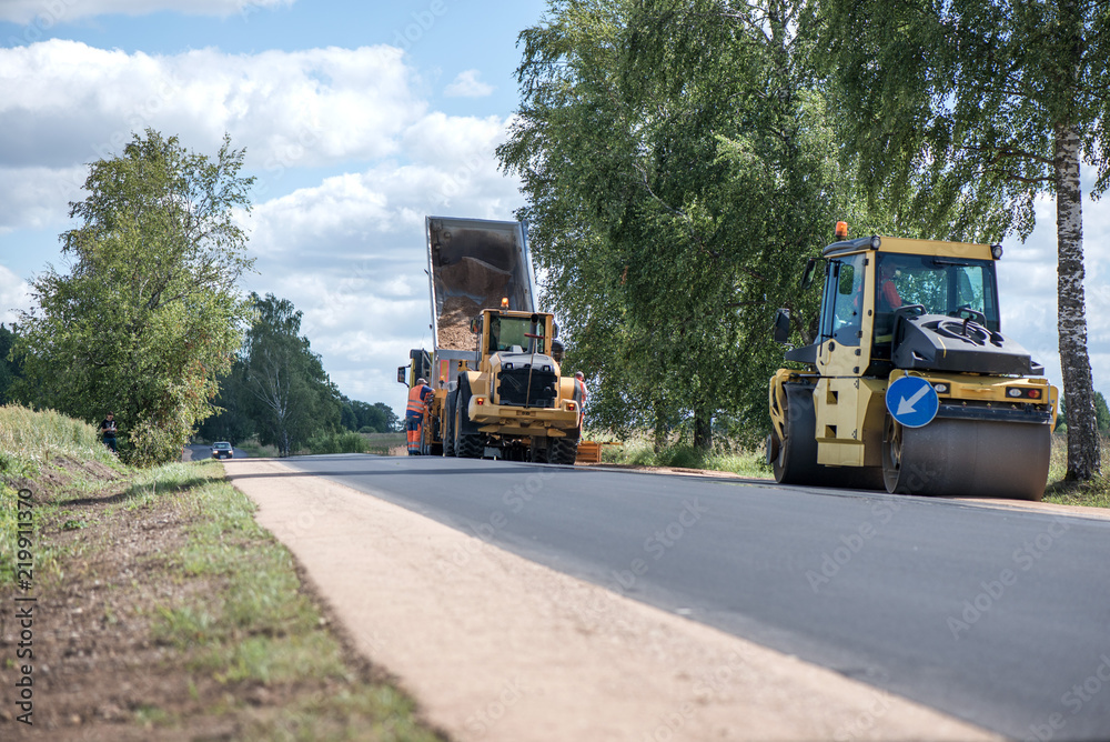 Road construction workers repairing highway road on sunny summer day. Loaders and trucks, heavy vibration roller compactor with arrow road sign on newly made asphalt. Work inspection with drone
Road construction workers repairing highway road on sunny summer day. Loaders and trucks, heavy vibration roller compactor with arrow road sign on newly made asphalt. Work inspection with drone