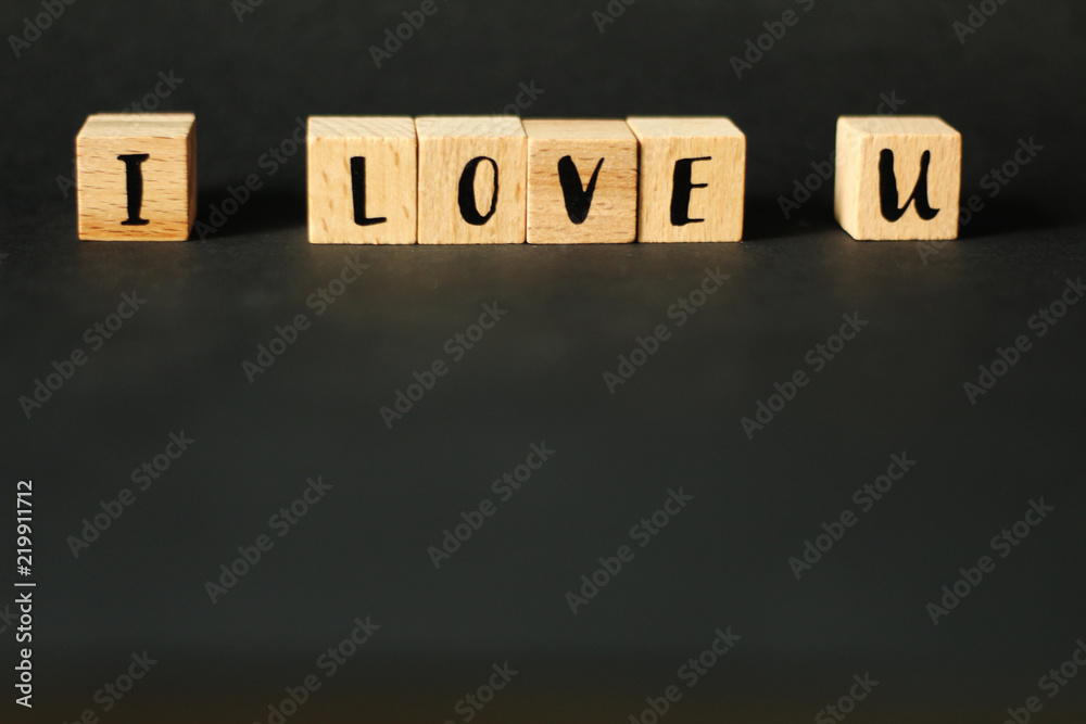 Obraz premium Word concept - I LOVE U build from wooden cubes with letters, selective focus, black background, free copy space