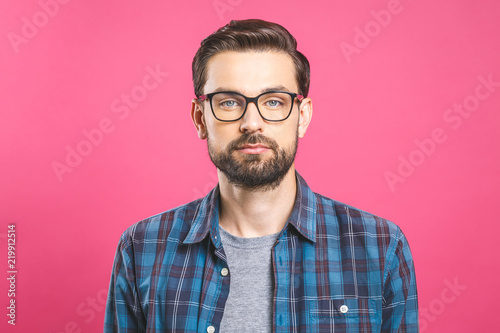 Serious young man in glasses with a beard on a pink background. No emotion on face. © denis_vermenko
