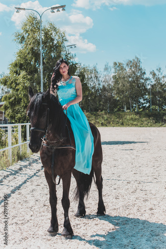 Romantic scene woman with a horse in the countryside. Concept of horse and human. Portrait of vintage style artistic woman walking with horse outdoors in turquoise dress