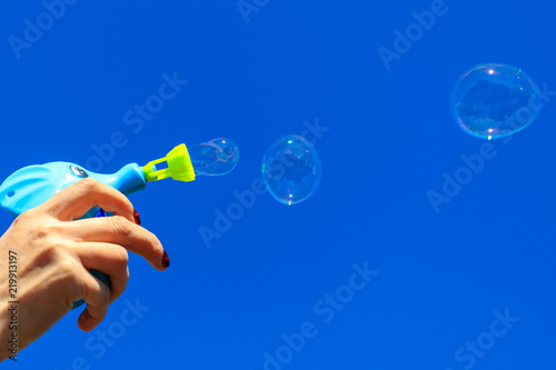 Hand with soap bubbles against the blue sky