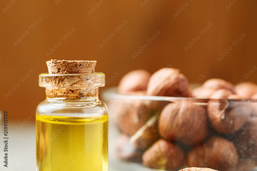 Small glass vial with wooden cork and different nuts in the background Small glass vial with wooden cork and different nuts in the background