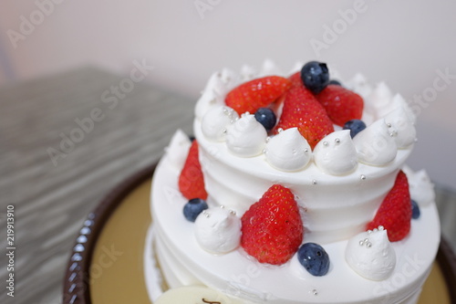 Birthday cake full of cream with strawberry and blue berry on top