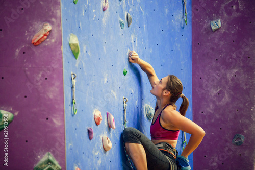 Photo of sports woman with talc bag behind back practicing on climbing wall