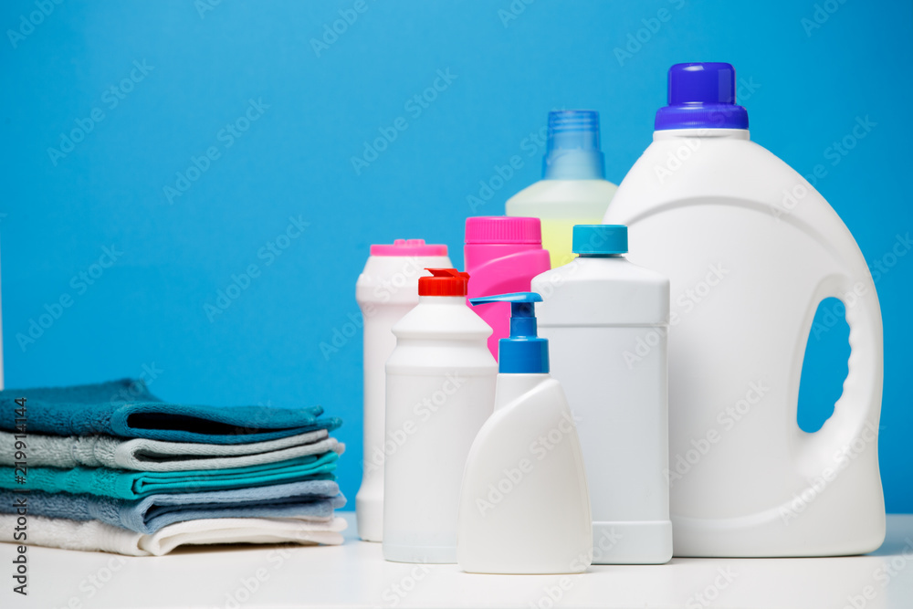 Photo of different bottles of cleaning products and colored towels isolated on blue background - obrazy, fototapety, plakaty 