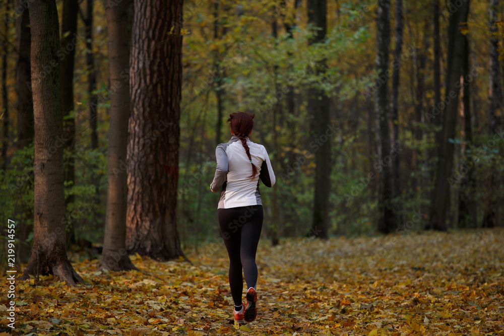 Photo from back in full growth of brunette running in forest Photo from back in full growth of brunette running in forest