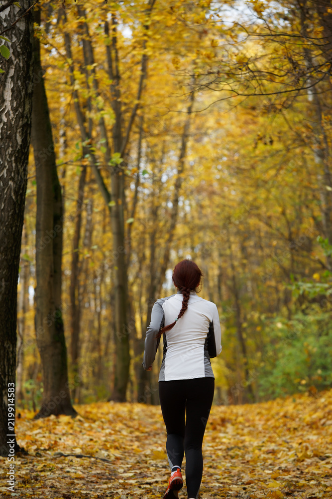 Photo from back in full growth of girl running on autumn foliage Photo from back in full growth of girl running on autumn foliage
