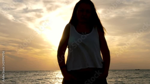 Silhouette of woman at the sea with a beautiful sceninc sunrise behind her. Travel and vacation photo