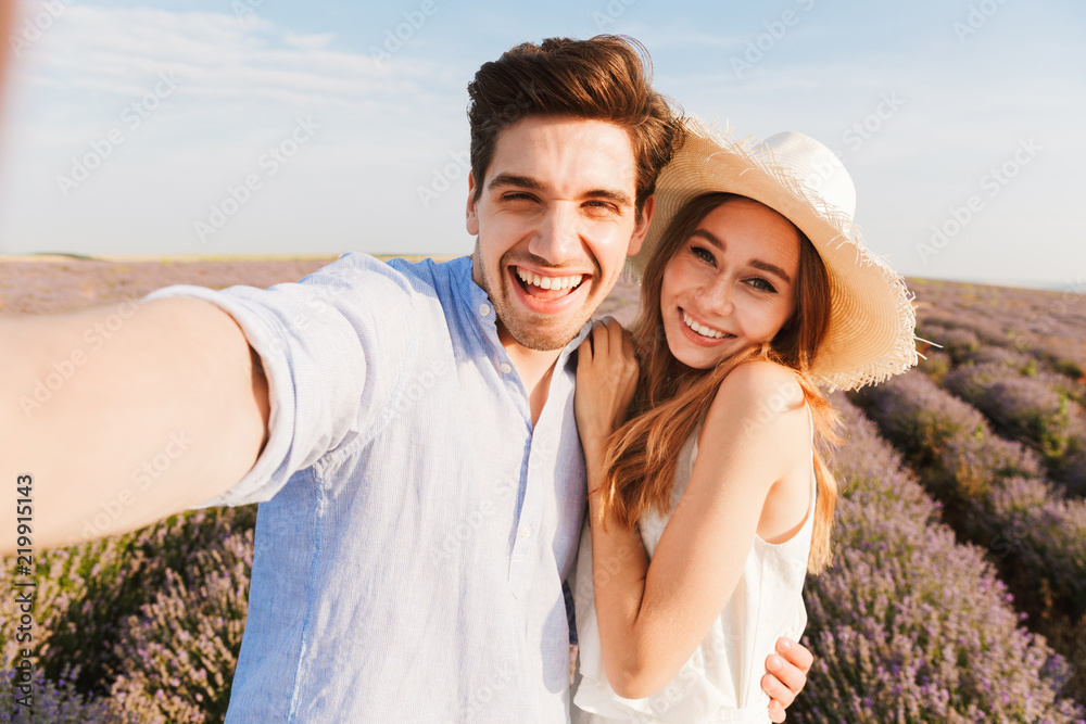 Obraz premium Beautiful young couple taking a selfie while hugging
