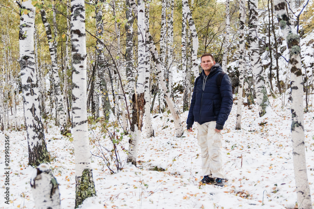 a man in a jacket is in the Birch forest