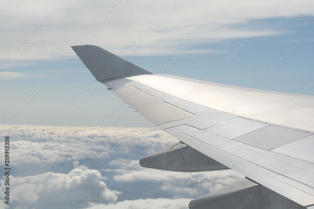 Airplane wing fliying above the clouds in clear sky Airplane wing fliying above the clouds in clear sky