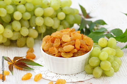 Dried raisins in a bowl and fersh grape photo