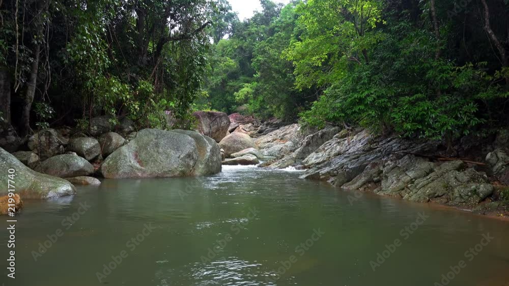 Fantasy lake with stone banks, Small waterfall or cascade falling down rocky slope and thicket of topical plants. Peaceful view of magical pond in mysterious enchanted forest. Koh Samui, Thailand. Fantasy lake with stone banks, Small waterfall or cascade falling down rocky slope and thicket of topical plants. Peaceful view of magical pond in mysterious enchanted forest. Koh Samui, Thailand.