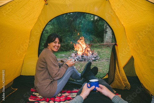 Obraz na plátne couple resting in tent with view on fire. woman drinking hot tea