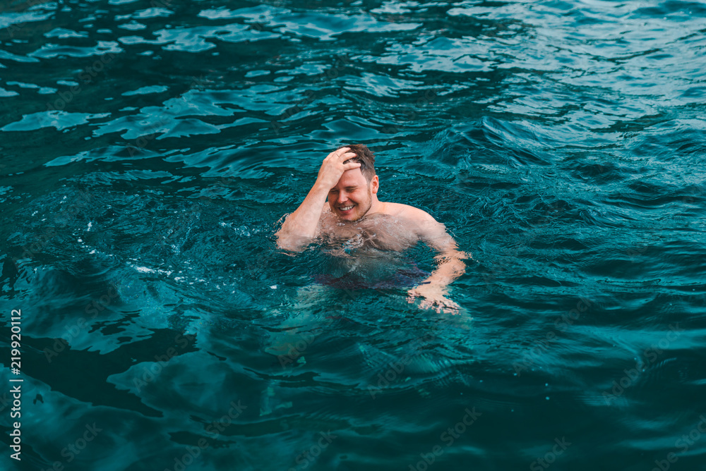 man swimming in blue transparent sea water