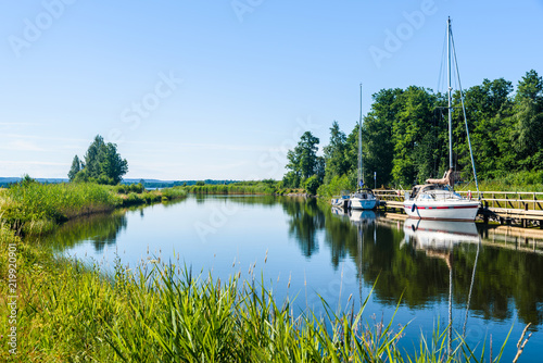The Gota canal at Tatorp, Sweden, on a sunny summer day. Sailboats moored by the pier. photo