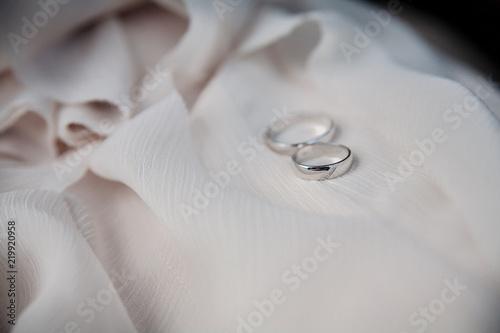 Two wedding gold rings lie on a cream wedding dress. close up