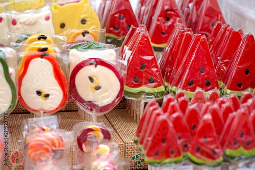 Natural honey sourced sweet candy in different shapes of fruits and colorful designs at a local state fair. Watermelon, pear, apple lollipop or jelly candy  
