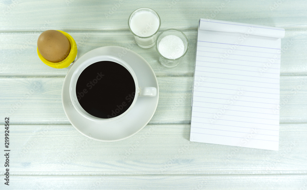 Hot coffee in the morning with milk and sugar in glass ,Soft-boiled egg in cup on a white wooden floor background,Top view Copy Space. Hot coffee in the morning with milk and sugar in glass ,Soft-boiled egg in cup on a white wooden floor background,Top view Copy Space.