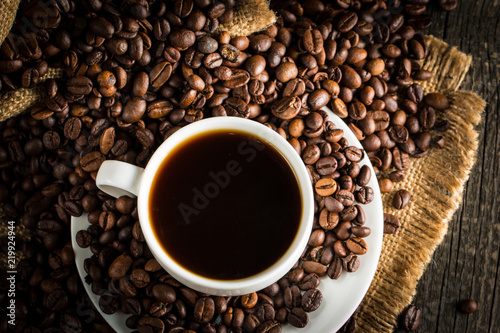 Coffee cup and beans on a rustic background. Coffee Espresso and a piece of cake with a curl. Cup of Coffee and coffee beans on table.